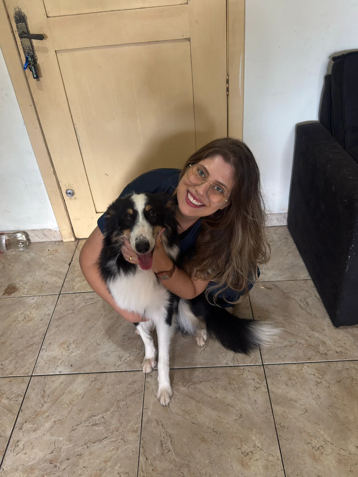Ratiba Baja abraçando um cão preto e branco